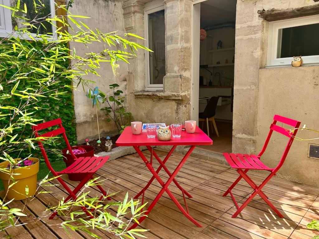 une table rouge et deux chaises sur la terrasse dans l'établissement Le Patio des Ducs, Hypercentre, à Dijon