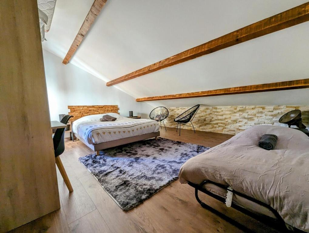 a bedroom with two beds and a stone wall at Magnifique Chalet avec Balneo in Roubion