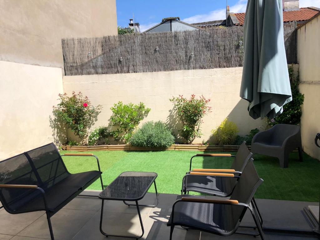 d'une terrasse avec des chaises, un parasol et une pelouse. dans l'établissement Maison de village avec jardinet, à Bruguières