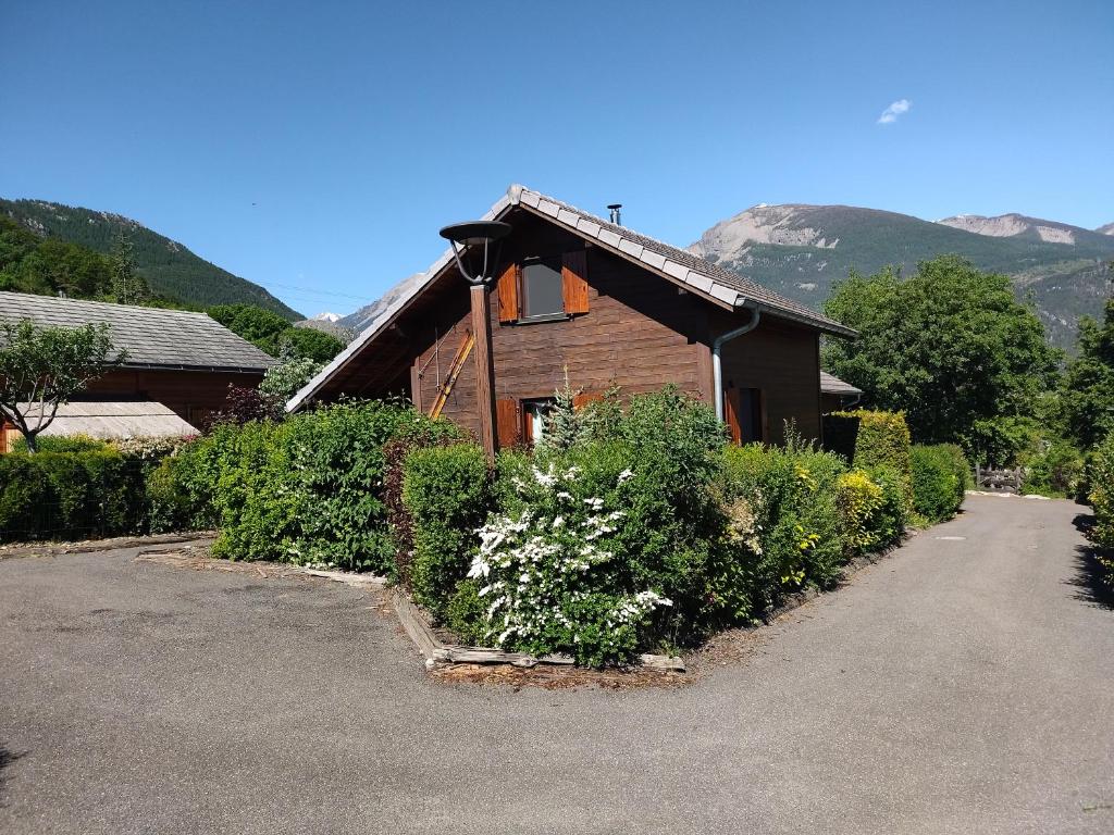 a wooden house with a lot of plants in front of it at CHALET MONTAGNE CLASSÉ 3 ETOILES ALPES QUEYRAs in Guillestre