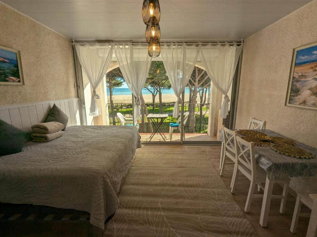 a bedroom with a bed and a table and a window at TRESOR LITTORAL, belle vue direct plage in Argelès-sur-Mer