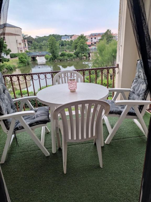 une table et des chaises sur un balcon avec vue sur une rivière dans l'établissement Le lac Bourgenay avec piscine du 1 mai au 15 sept, à Talmont-Saint-Hilaire