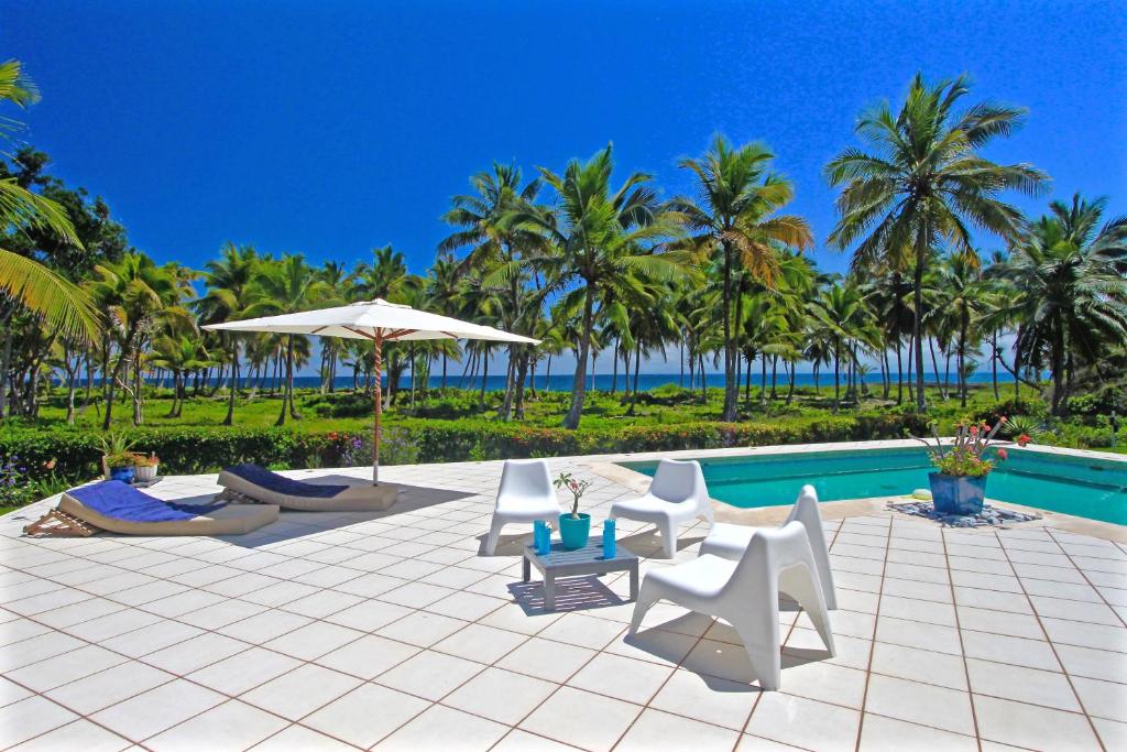 a patio with chairs and an umbrella next to a pool at Villa Talanquera in Las Galeras