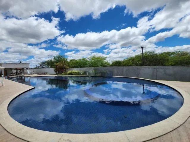 una gran piscina con cielo azul y nubes en Apart no condomínio Residencial Ipojuca, en Caruaru