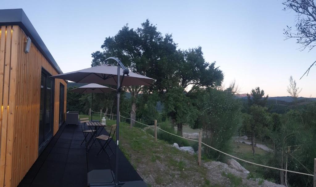 a patio with an umbrella and tables and chairs at Casa d' Além Turismo e Natureza - Refúgio do Bosque in Torneiro