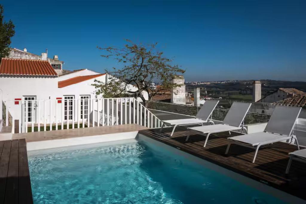 a swimming pool with two chairs next to a house at Segredos da Muralha in Óbidos