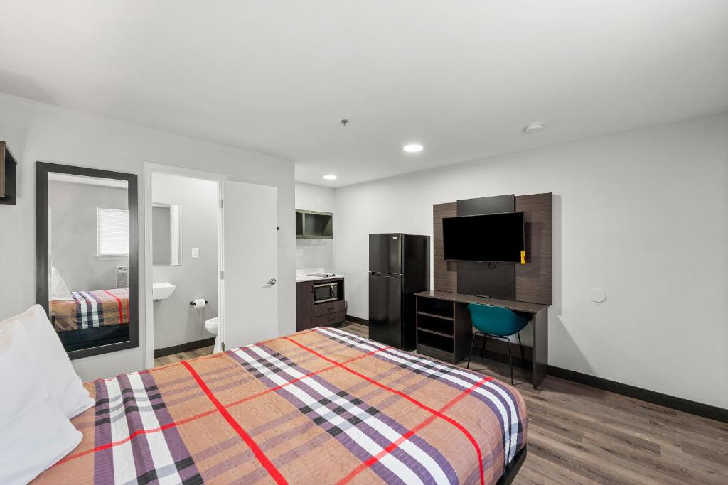 une chambre avec un lit et un bureau avec une télévision dans l'établissement Southern Suites Kennesaw, à Kennesaw