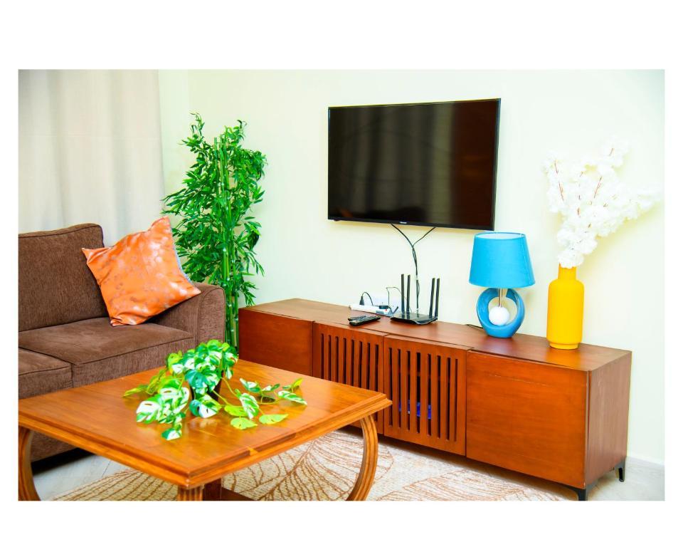 a living room with a couch and a table with a tv at Cherryhomes at Mbezi Juu in Dar es Salaam