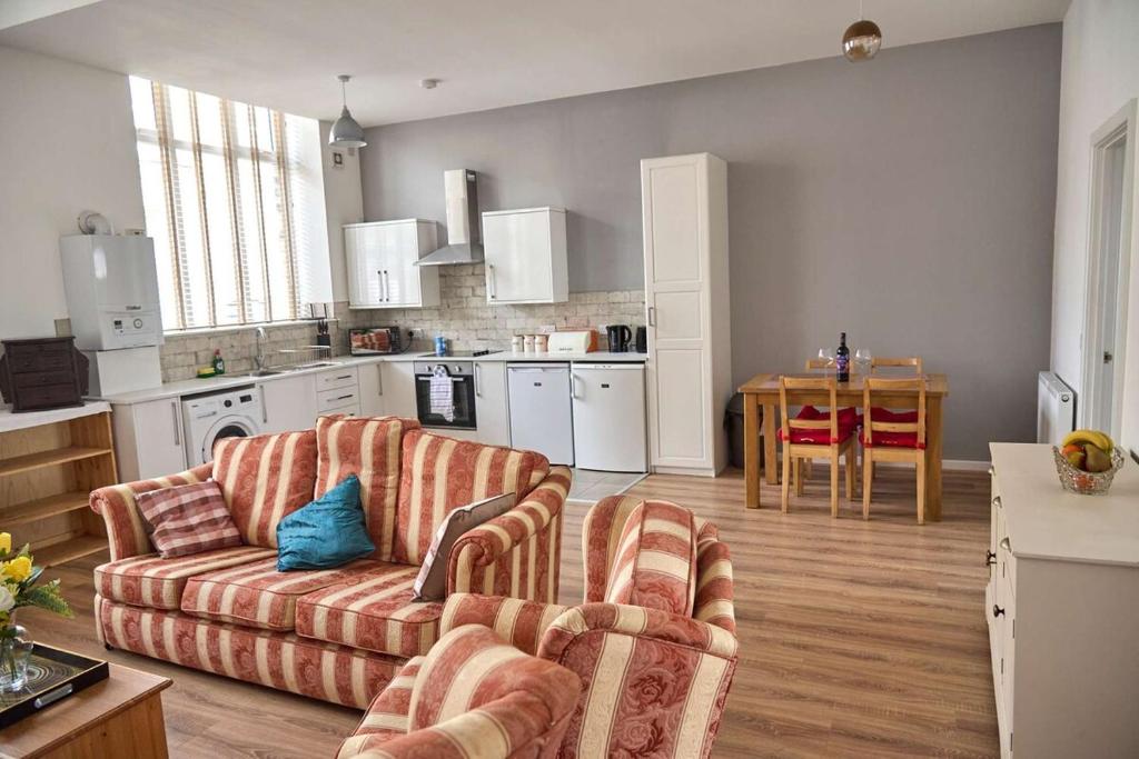 a living room with two couches and a kitchen at Iconic Apartment - Littleborough in Littleborough