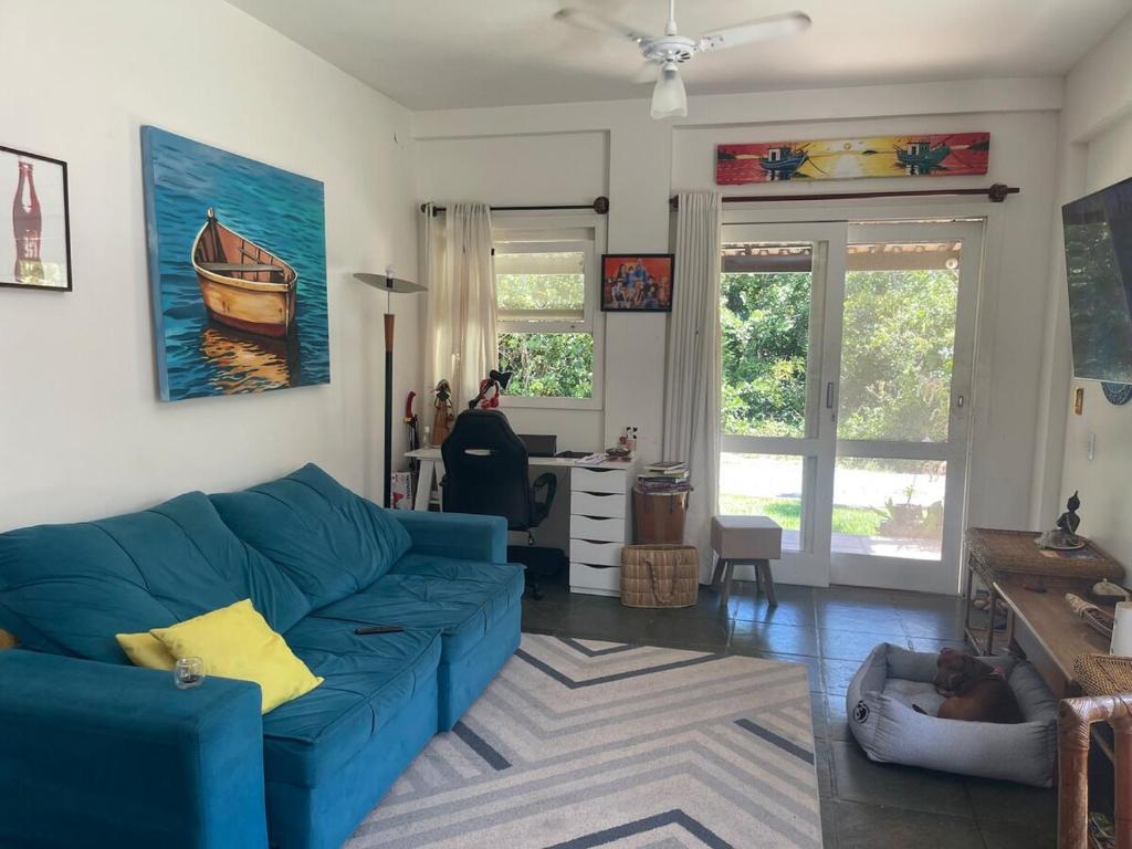 ein Wohnzimmer mit einem blauen Sofa und einem Schreibtisch in der Unterkunft Casa perto do mar, conforto em meio a natureza in Búzios