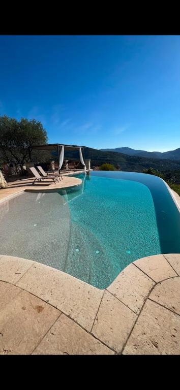 une grande piscine d'eau bleue avec des montagnes en arrière-plan dans l'établissement Maison Lou, à Falicon