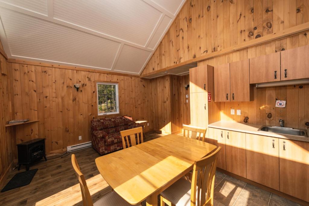 a kitchen with a wooden table and a dining room at Chalet des Boisés 10 in Murdochville