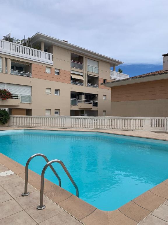 une grande piscine devant un immeuble dans l'établissement Cocon plage avec piscine, à côté du port et plage de sable fin, à Vallauris