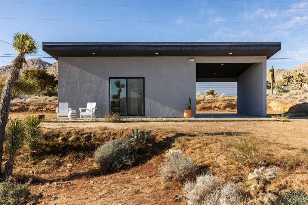a house in the desert with two white chairs at modern casita | Joshua Tree tiny home in Joshua Tree