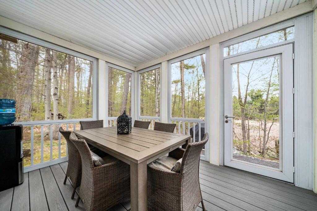 a screened in porch with a wooden table and chairs at The Tree Frog - 12 Pine Forest in Cherry Valley