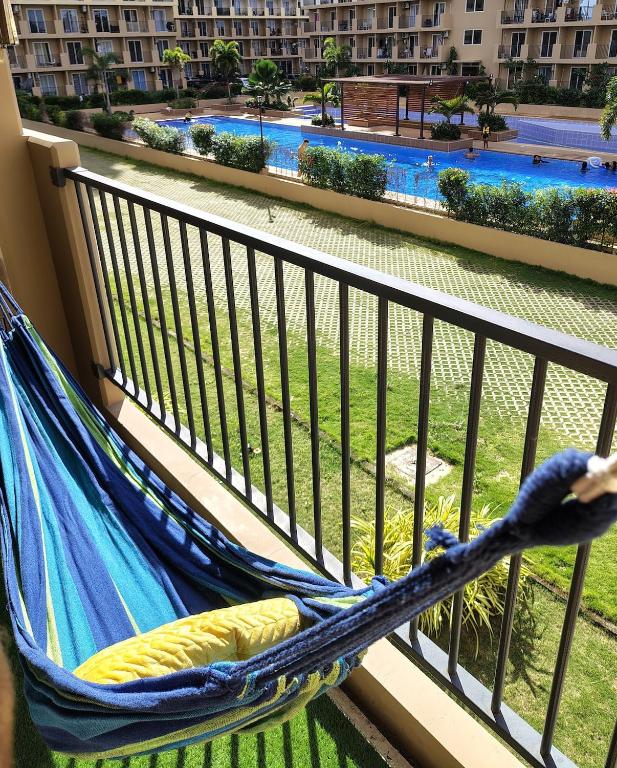 a hammock on a balcony with a view of a pool at Homey Apartment with Olympic-sized pools in Lapu Lapu City