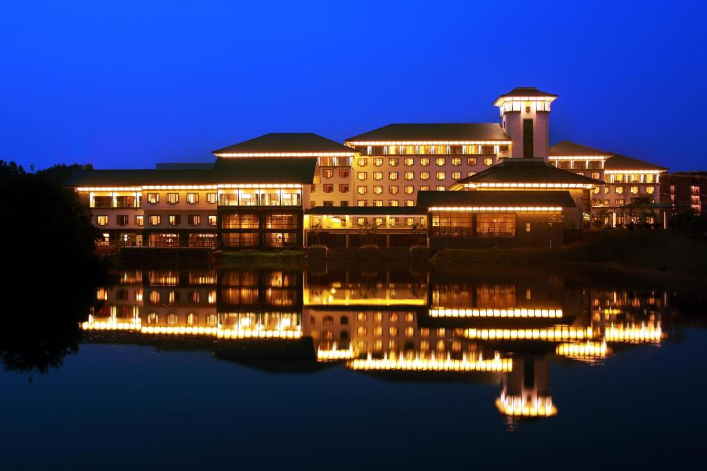 un edificio con luces en el agua por la noche en Gloria Resorts Jingdezhen Xishan Lake, en Jingdezhen
