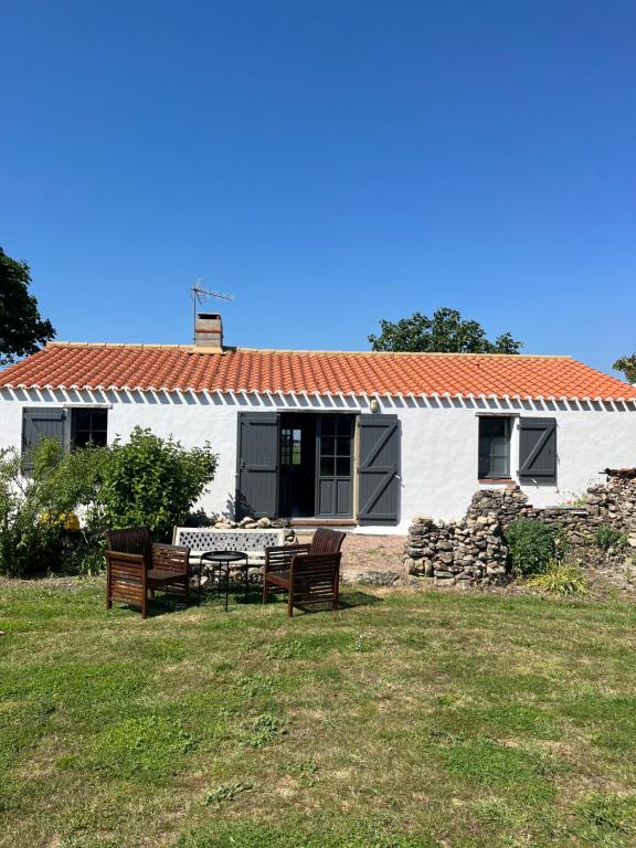 une maison blanche avec une table et des chaises dans la cour dans l'établissement Maison L union, à Beauvoir-sur-Mer