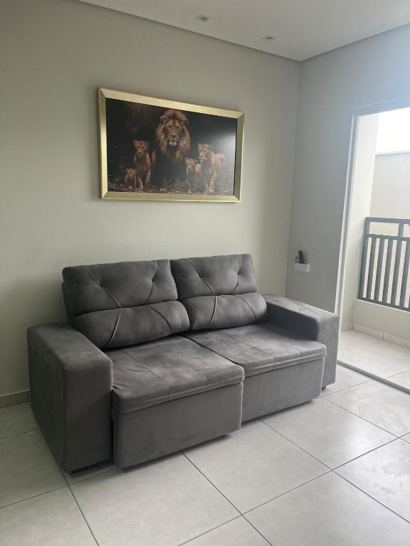 a couch in a living room with a painting on the wall at Apartamento próximo avenida da Semi Jóia in Limeira