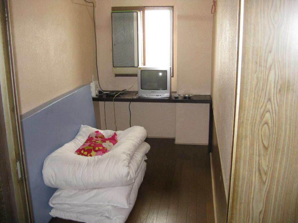 a small room with a white chair and a television at Hotel Diamond in Osaka