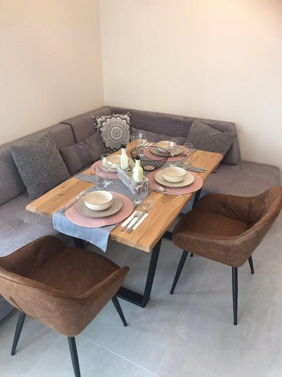 a wooden table with chairs and a couch at Апартаменти ''Димови'' in Lozenets