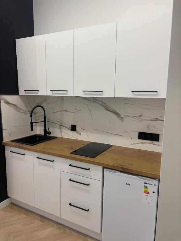 eine weiße Küche mit weißen Schränken und einer Spüle in der Unterkunft Drzewna Apartamenty-Wojska Polskiego in Zielona Góra