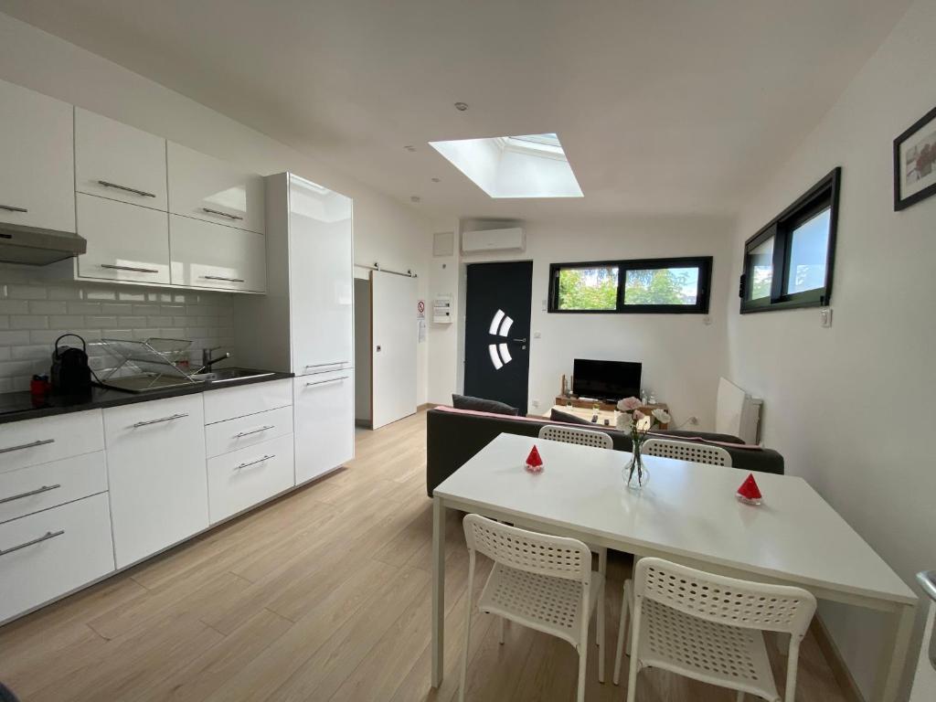 kuchnia z białymi szafkami, stołem i krzesłami w obiekcie Appartement paisible proche centre ville w mieście Bron