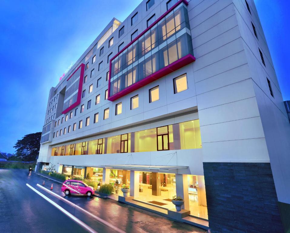 un coche rojo estacionado frente a un edificio en favehotel Hyper Square, en Bandung