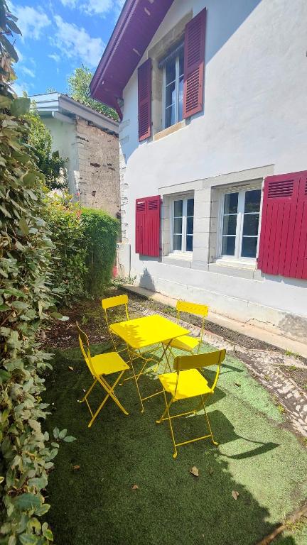 une table et des chaises jaunes devant un bâtiment dans l'établissement Appartement Bayonne dans maison basque avec jardin, à Bayonne