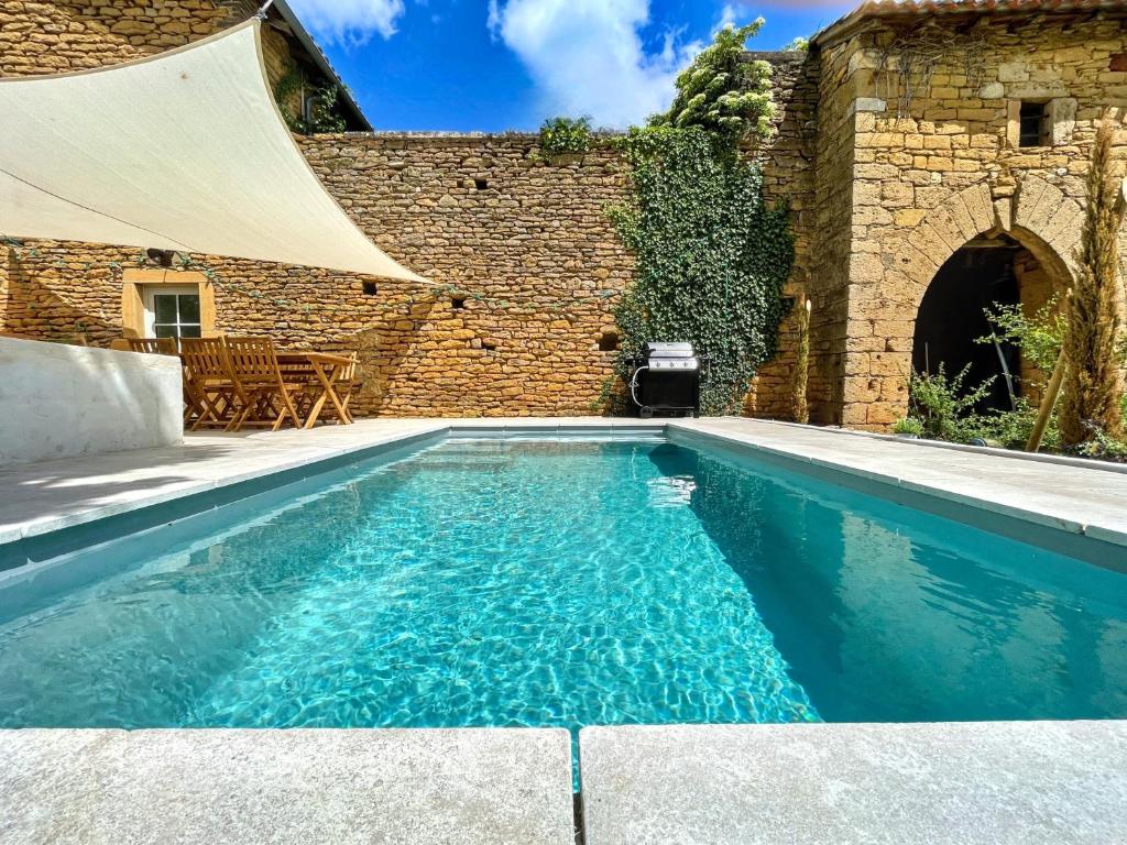 a swimming pool in front of a brick building at L'Heure dorée, au coeur du Beaujolais in Lacenas