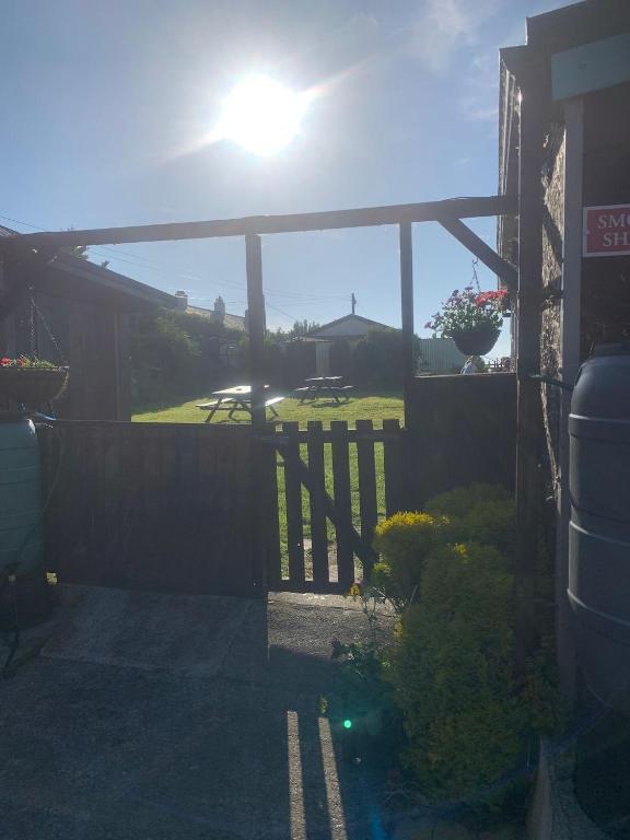 a view of a yard with a fence and the sun at The Chisel Coach House at The Bettle and Chisel in Delabole