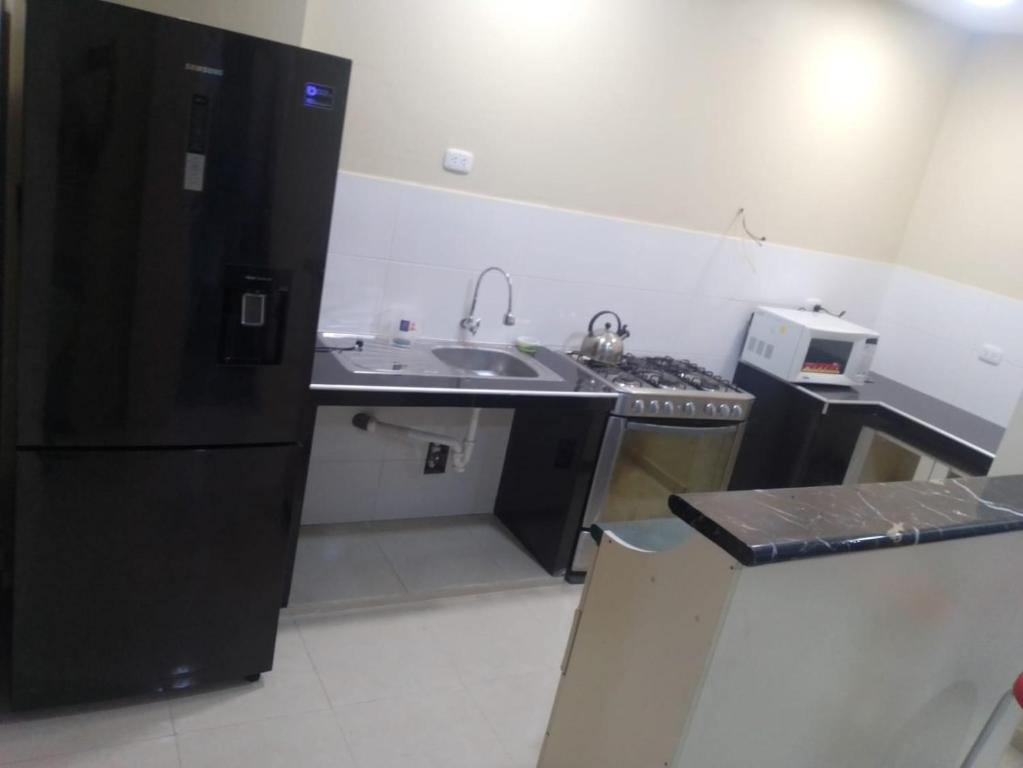 Una pequeña cocina con fregadero y refrigerador. en Residencia, en Lima