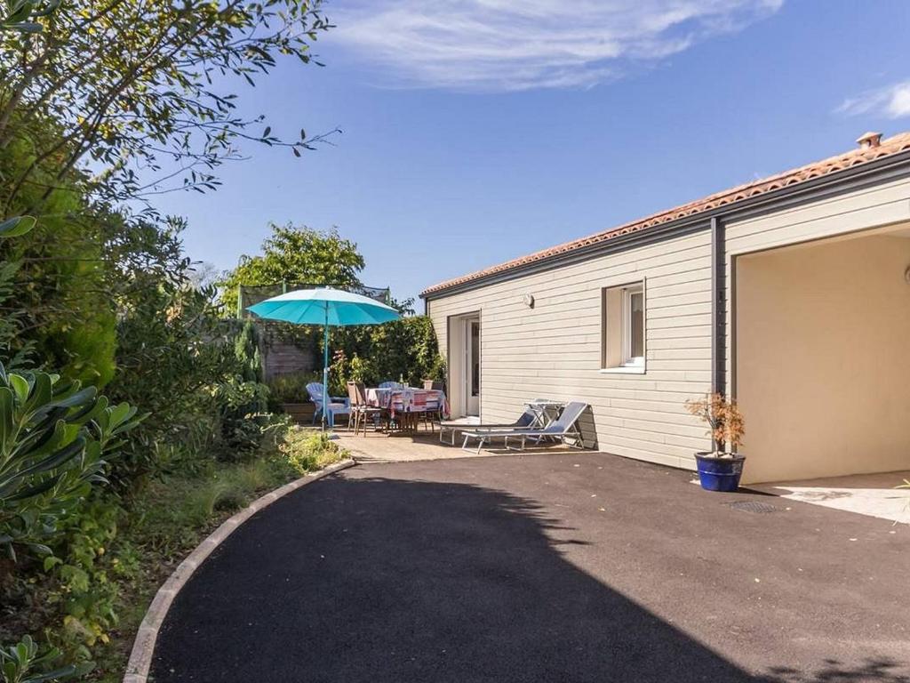 - une terrasse avec un parasol à côté d'un garage dans l'établissement Maison de charme à Pornic avec jardin, proche des plages et commerces, clim et wifi inclus - FR-1-306-1038, à Pornic