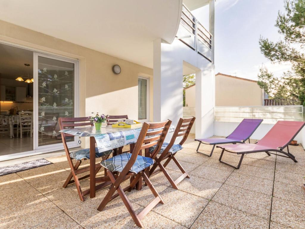 un patio avec une table et des chaises en bois dans l'établissement Appartement Calme Proche Plage avec Terrasse Sud, Parking Sécurisé et Équipements Complets - FR-1-306-909, à Saint-Brévin-les-Pins
