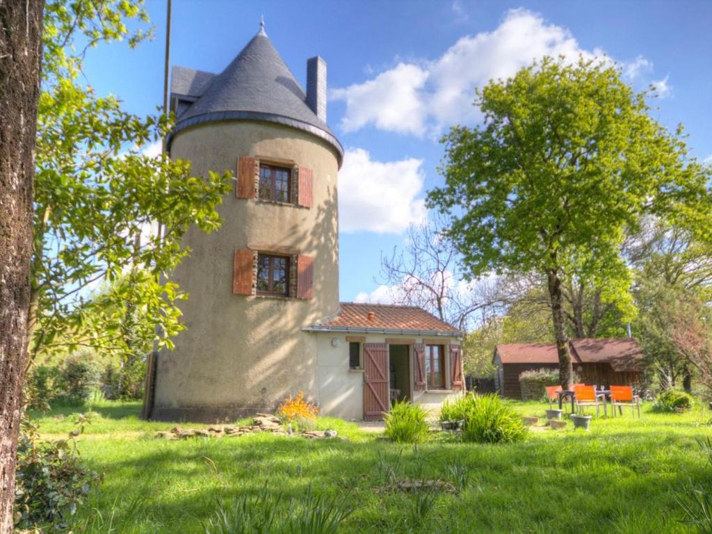 une maison avec une tour au milieu d'un champ dans l'établissement Moulin rénové avec jardin clos près de Pornic - FR-1-306-872, à Pornic