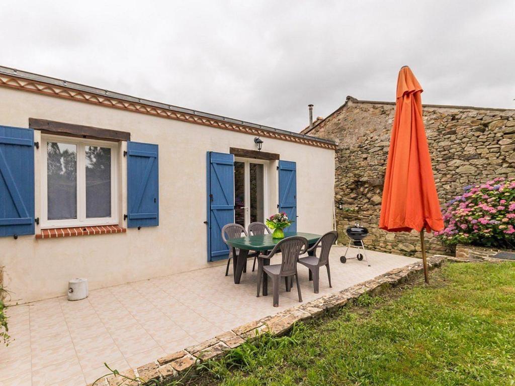 a patio with a table and an umbrella at Gîte familial avec jardin clos, à 25 km de Nantes, WiFi, vélos et jeux pour enfants. - FR-1-306-953 in Rouans