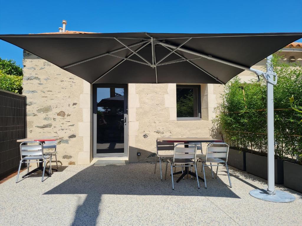 ein großer schwarzer Regenschirm über einem Tisch und Stühlen in der Unterkunft Charmant studio rénové avec mezzanine, cour privative et parking à Rochetrejoux - FR-1-426-479 in Rochetrejoux