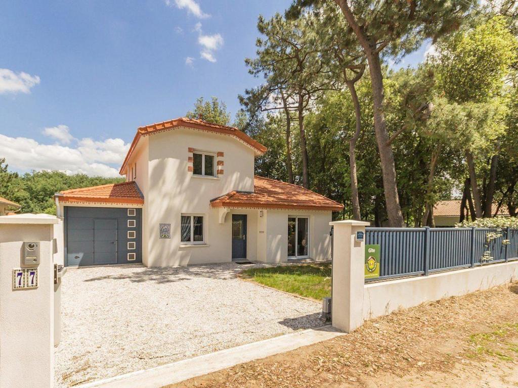 une maison blanche avec un portail et une clôture dans l'établissement Maison Neuve en Bord de Mer avec Jardin Boisé, Wifi, et Équipements Complets - FR-1-306-1096, à Saint-Brévin-les-Pins