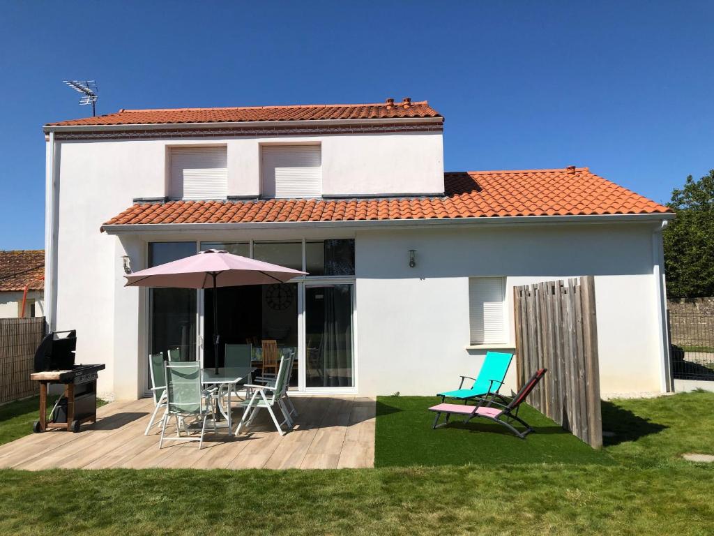 une maison avec une terrasse dotée de chaises et d'un parasol dans l'établissement Gîte calme proche mer à Pornic, jardin clos, accessible PMR, visite ferme, wifi, équipement bébé - FR-1-306-1067, à Pornic