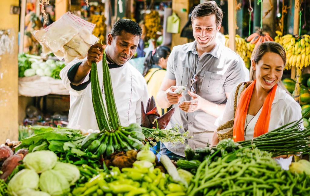 a group of people standing in a market with vegetables at Anantara Peace Haven Tangalle Resort in Tangalle