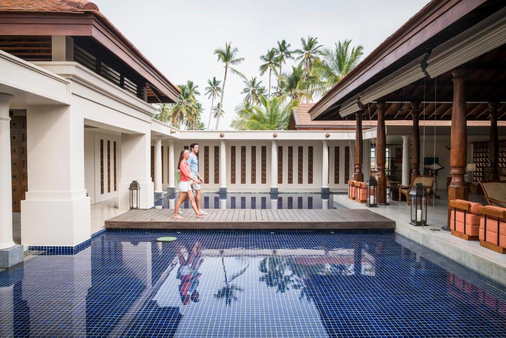 a woman walking by a swimming pool in a house at Anantara Peace Haven Tangalle Resort in Tangalle