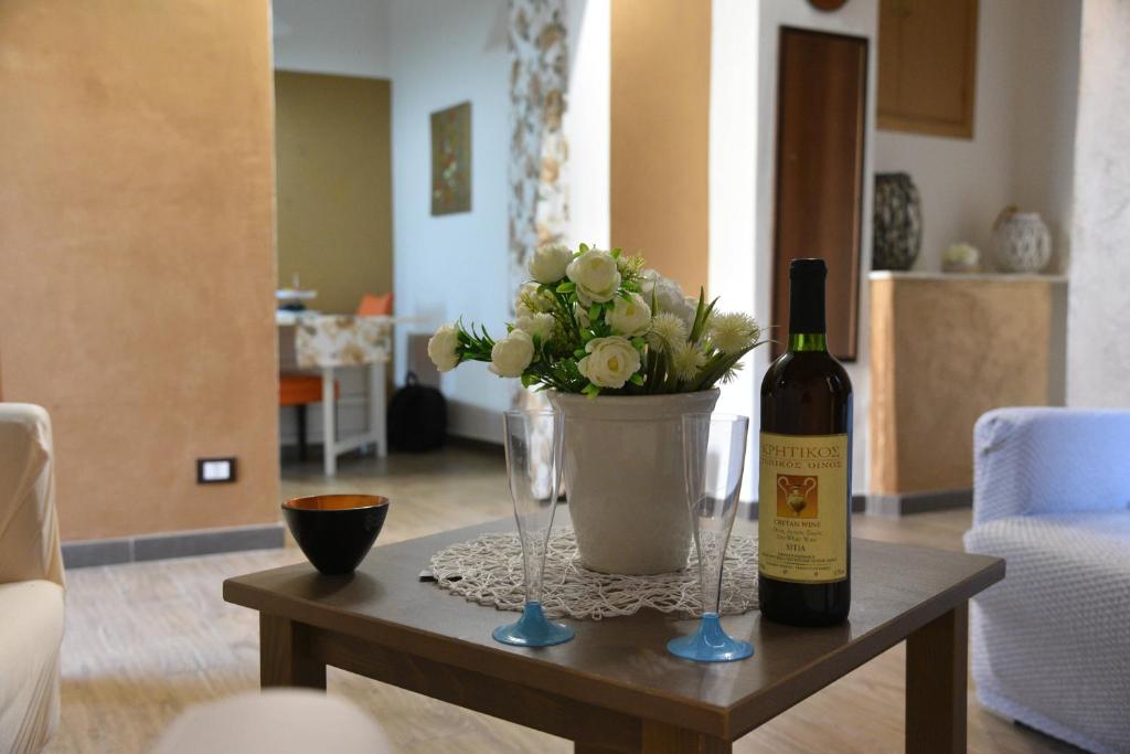 a table with a bottle of wine and a vase with flowers at Appartamento in centro- Enea home in Agrigento