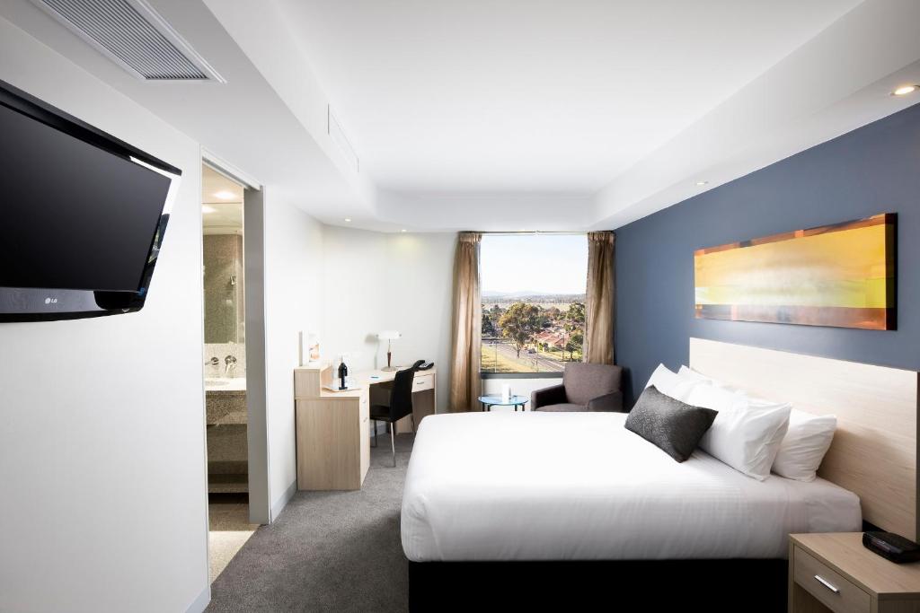 Mantra Melbourne Airport في ملبورن: غرفة فندقية بسرير وتلفزيون بشاشة مسطحة