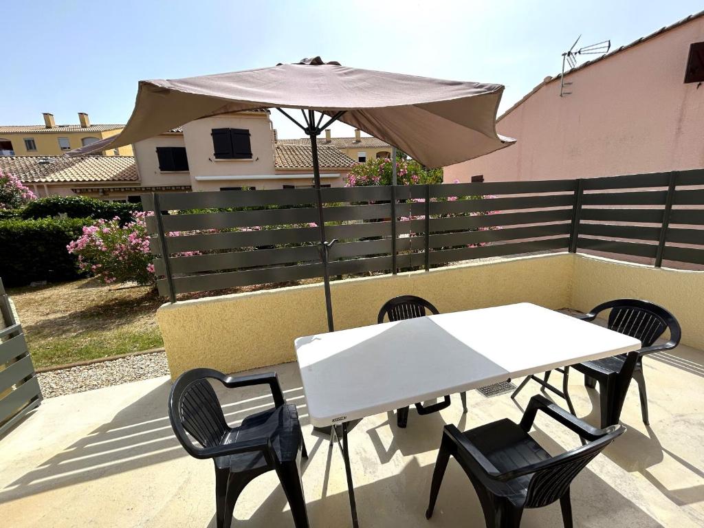 une table et des chaises avec un parasol sur une terrasse dans l'établissement Maison proche plage avec terrasse et parking - FR-1-837-8, à Argelès-sur-Mer