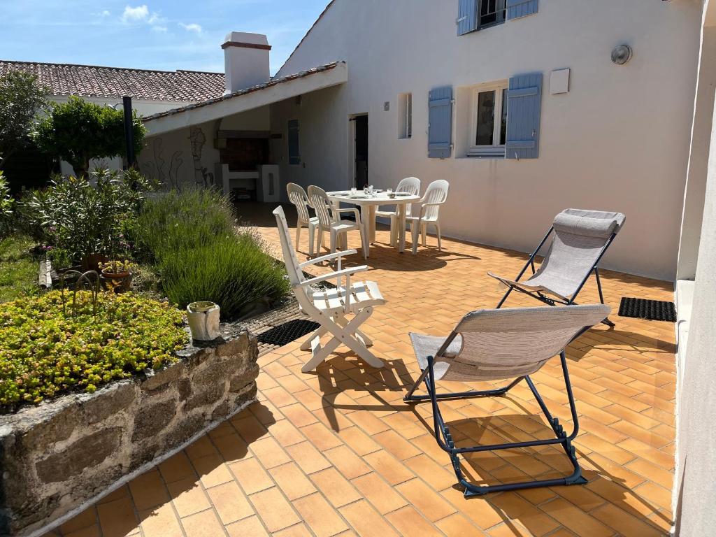 d'une terrasse avec des chaises et une table dans la cour. dans l'établissement Maison à Noirmoutier 6 pers, Animaux admis, Wifi - FR-1-823-158, à Noirmoutier-en-l'lle
