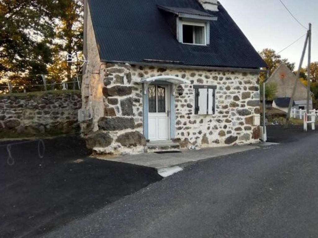 una casa de piedra con una puerta blanca y un techo negro en Maison de charme à Cros - 3 pers, Parc des Volcans - FR-1-814-133, en Cros