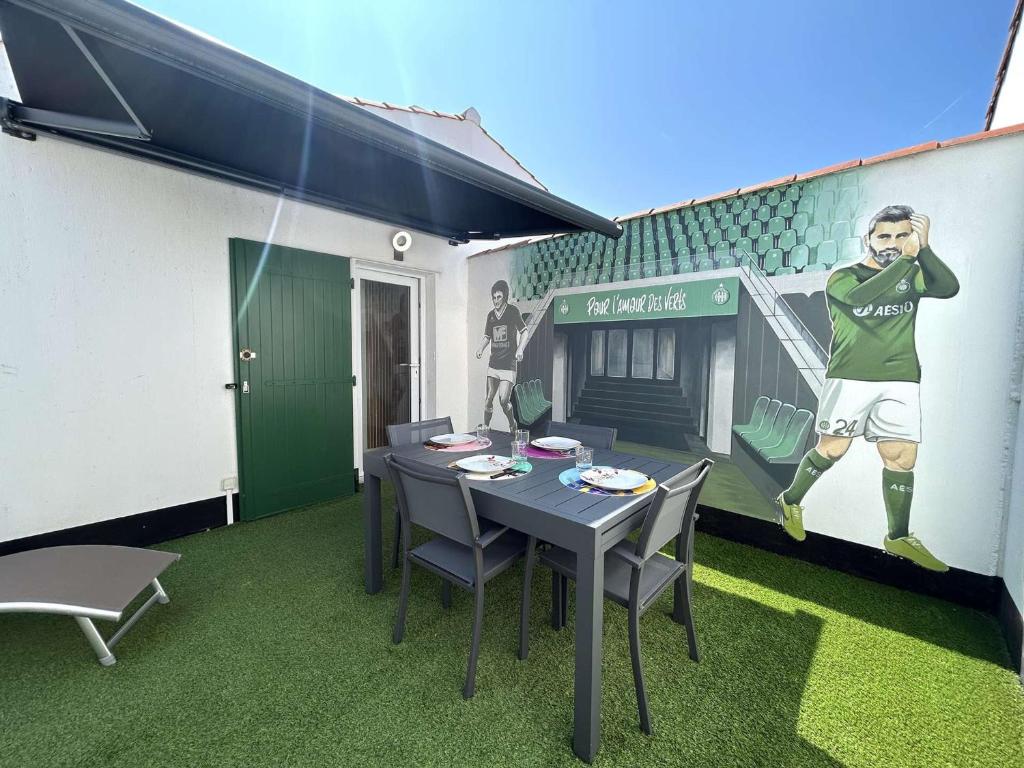 une table avec des chaises et un tableau d'un joueur de football dans l'établissement Maison 2 pièces à 600m de la mer avec parking privé - FR-1-224A-77, à Bretignolles-sur-Mer