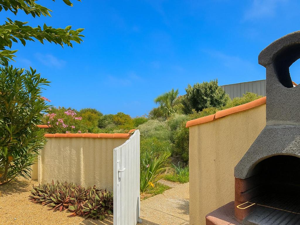 une clôture avec un portail blanc dans une cour dans l'établissement Maison en bord de plage avec parking et 2 chambres | Torreilles - FR-1-732-79, à Torreilles