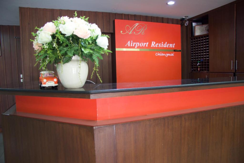 a reception counter with a vase of flowers on it at Airport Resident in Chiang Mai