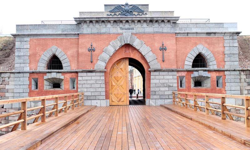 a brick building with a yellow door and a wooden deck at Picturesque apartment into antique fortress in Daugavpils